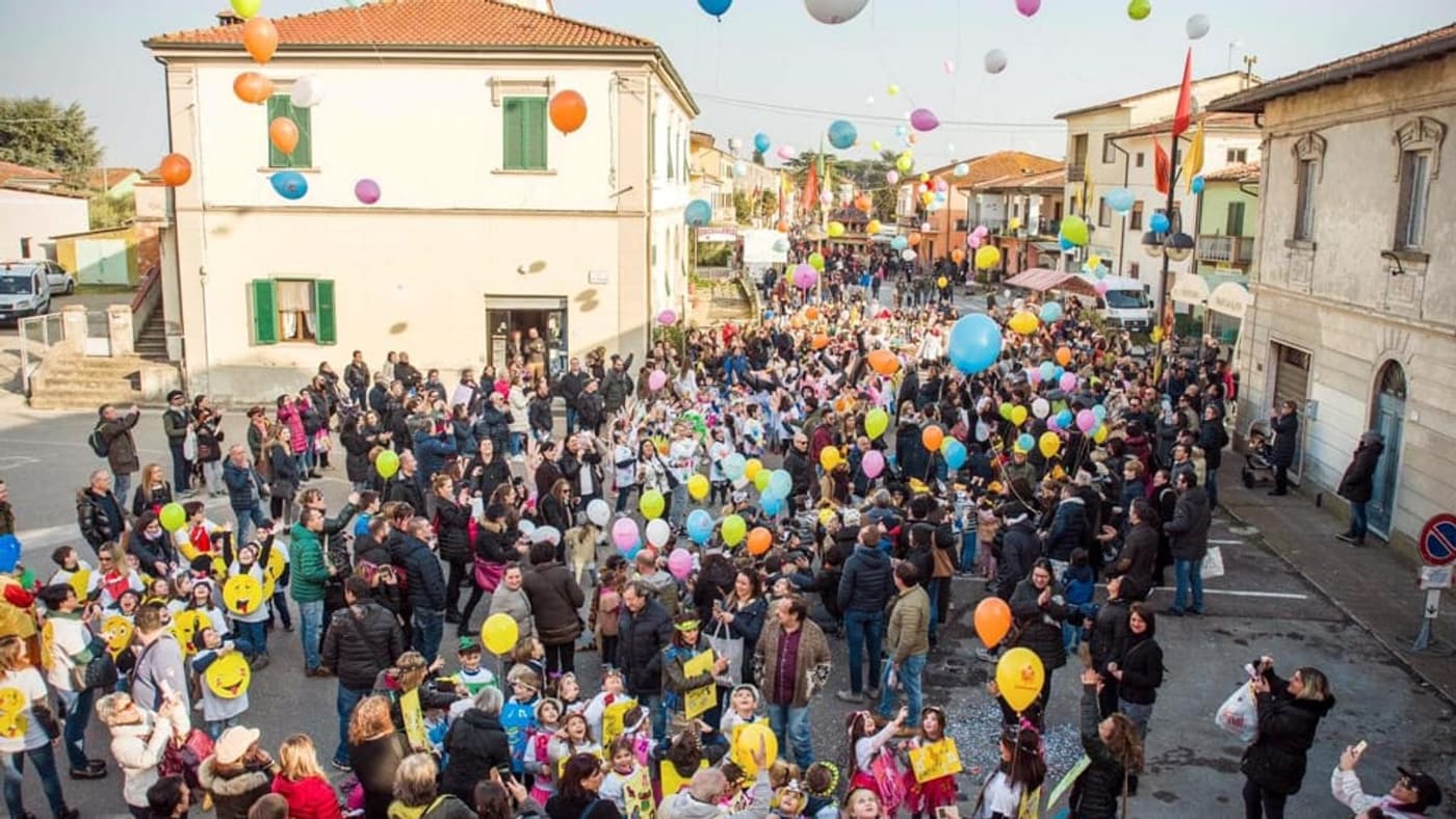 Hundreds of balloons rise over a crowded village square full of families during a recent Carnevale